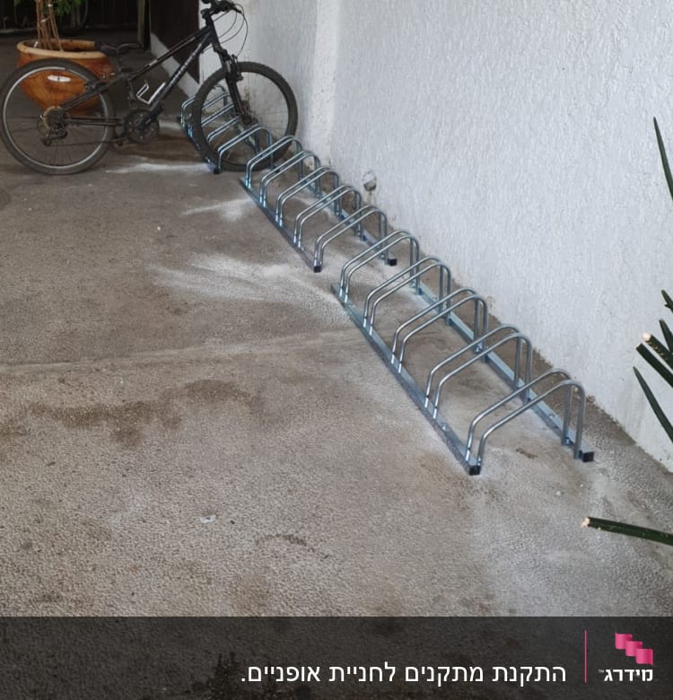 אופניים חונים במתקן מתכת על קיר חיצוני